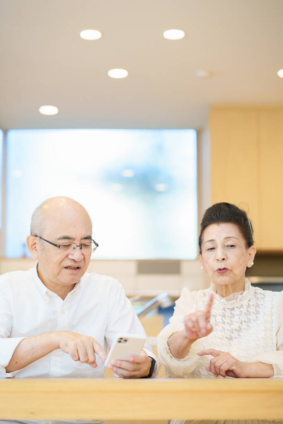 Senior couple using smartphones through trial and error in the room - Photo, Image