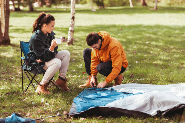 happy couple setting up tent outdoors - Foto, afbeelding