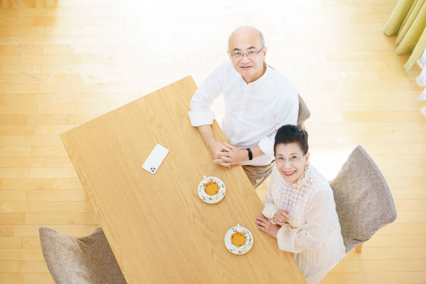 Starší pár chatuje s úsměvem v obývacím pokoji - Fotografie, Obrázek