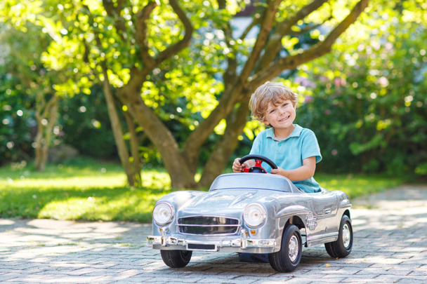 Маленький хлопчик водить велику іграшкову стару машину, на відкритому повітрі
 - Фото, зображення