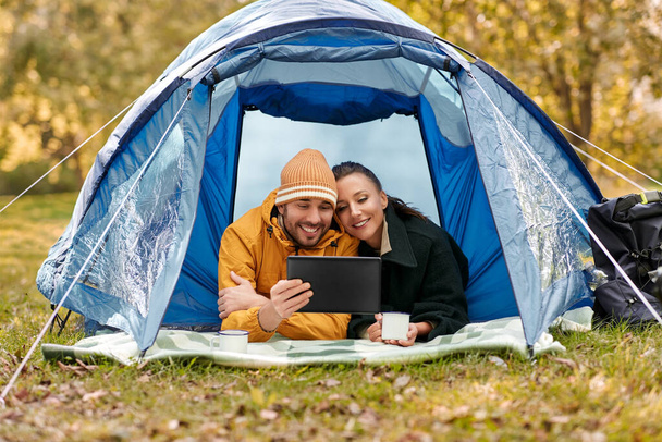 couple with tablet pc drinking tea inside tent - Фото, зображення