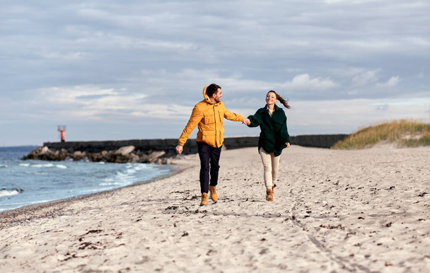 couple running along autumn beach - Φωτογραφία, εικόνα