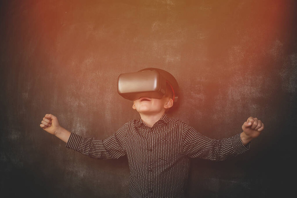 Dziecko w VR. Zestaw słuchawkowy wirtualnej rzeczywistości na głowie. Dzieciak ze szkoły odkrywa planetę. Szczęśliwe zszokowane dziecko. - Zdjęcie, obraz
