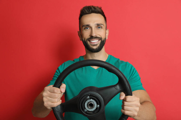 Happy man with steering wheel on red background - Фото, изображение