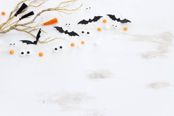 top view image of Halloween holoday. witcher broom, bare trees, treats and bats over white wooden table - Фото, зображення