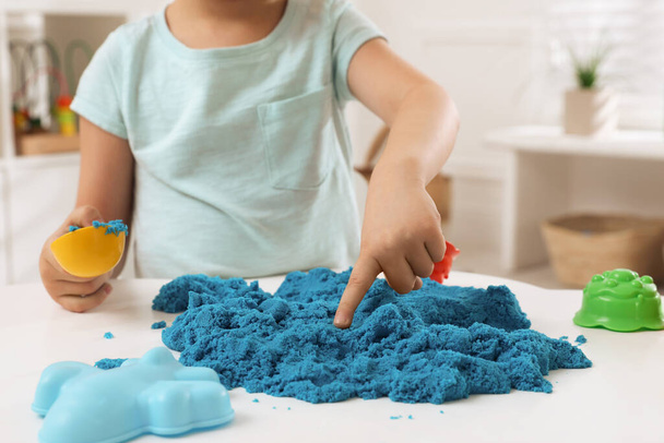 Little boy playing with bright kinetic sand at table indoors, closeup - Fotografie, Obrázek