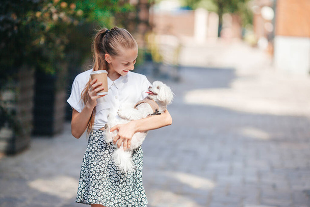 Pequena menina sorridente brincando e abraçando filhote de cachorro no parque - Foto, Imagem