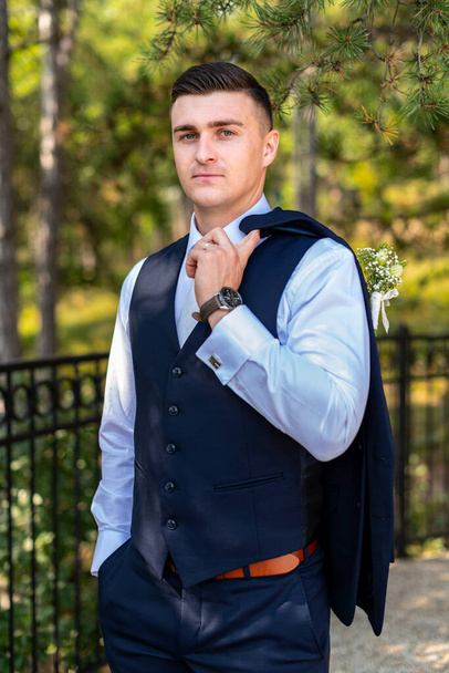Handsome young groom wearing elegant dark blue suit looking at camera outdoors  portrait. Stylish groom fashion. - Zdjęcie, obraz