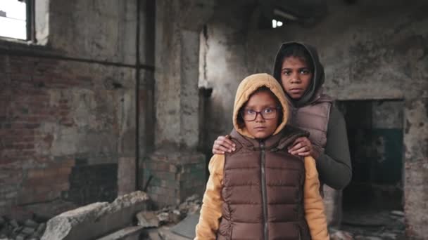 Średni portret dwóch afro-amerykańskich uciekinierek patrzących w kamerę stojących razem w ruinach zburzonego domu - Materiał filmowy, wideo