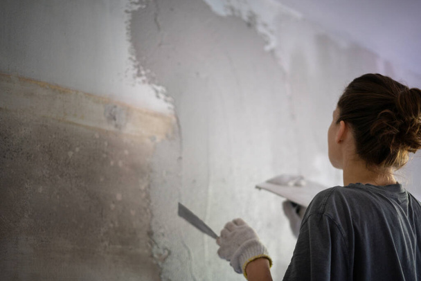 Young woman doing home repairs by applying plaster using a trowel - Fotografie, Obrázek