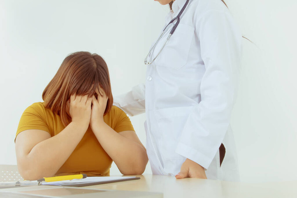 Medical care concept : Young Asian obese women are depressed and worried about their illness while the female doctor enters a positive shoulder and encourages them to treat the illness. - Foto, Imagen