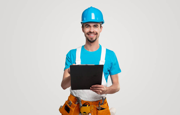 Smiling contractor with clipboard looking at camera - 写真・画像