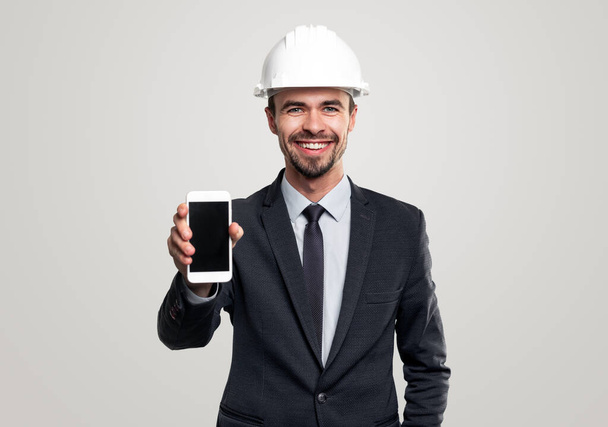 Cheerful male engineer showing smartphone - Photo, Image