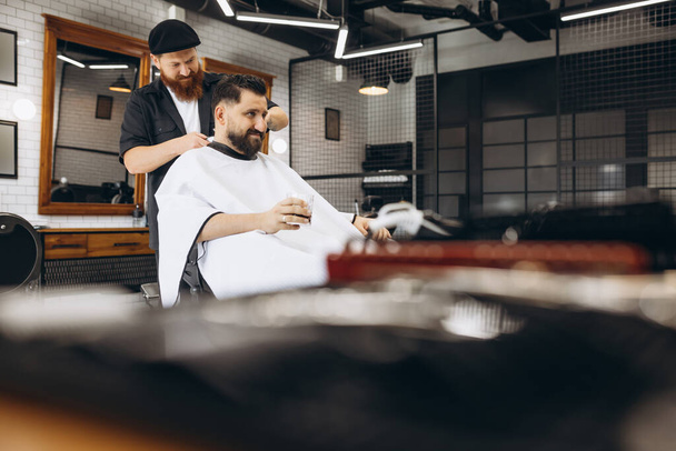 Professional barber, clipper making hair cut to customer, young man at barbershop. Beauty, selfcare, style, fashion and male cosmetics concept. - Fotografie, Obrázek