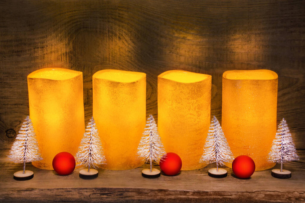 4 χρυσά ηλεκτρικά κεριά LED και χριστουγεννιάτικη διακόσμηση σε ξύλινο φόντο - Φωτογραφία, εικόνα