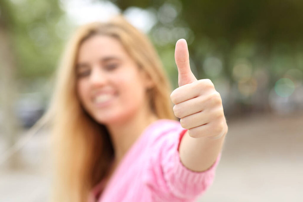 Happy blurred teen gesturing thumb up at camera in the street - Foto, Bild