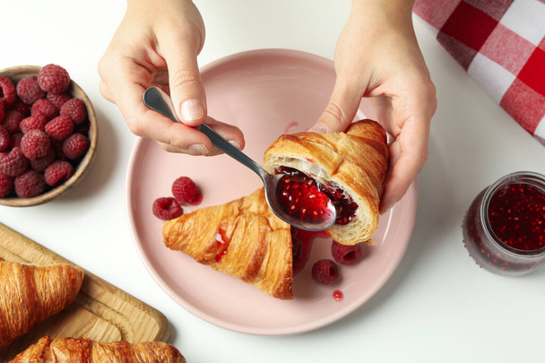 Concept de manger savoureux avec croissant avec confiture de framboises sur fond blanc - Photo, image