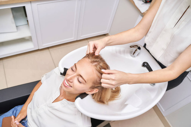 Long hair procedure. Hairwash at salon. Woman master. Hand with towel. Adult - Fotó, kép