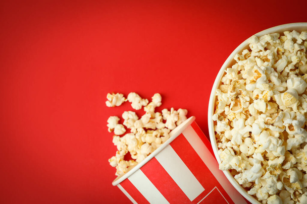 Pappbecher mit Popcorn auf rotem Hintergrund. - Foto, Bild
