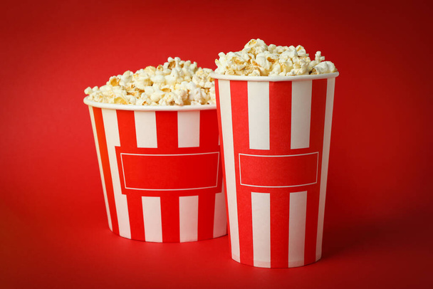 Paper cups with popcorn on red background. - Photo, Image