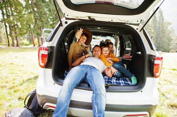 Family at vehicle interior. Father with four kids. Children in trunk. Traveling by car in the mountains, atmosphere concept. - Фото, изображение