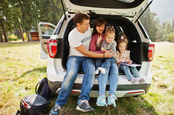 Family with two baby girls at vehicle interior. Children in trunk. Traveling by car in the mountains, atmosphere concept. - Photo, Image