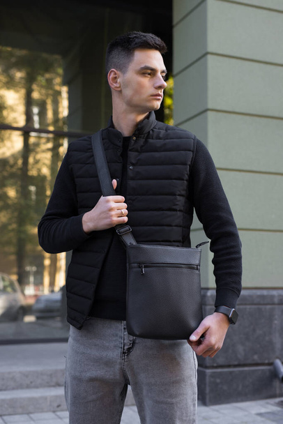 Man holding messenger bag in a city - Fotoğraf, Görsel
