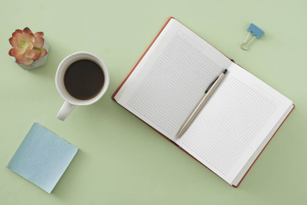 Fondo de oficina o de negocios con cuaderno abierto y bolígrafo en verde con bloc de notas pegajoso, flor y taza de café en una vista plana - Foto, Imagen