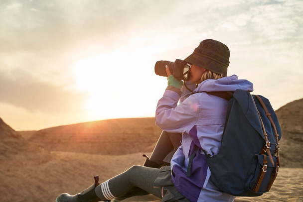 asian woman female photographer taking a photo of landscape in gobi desert with yardang landforms at sunset - Photo, Image