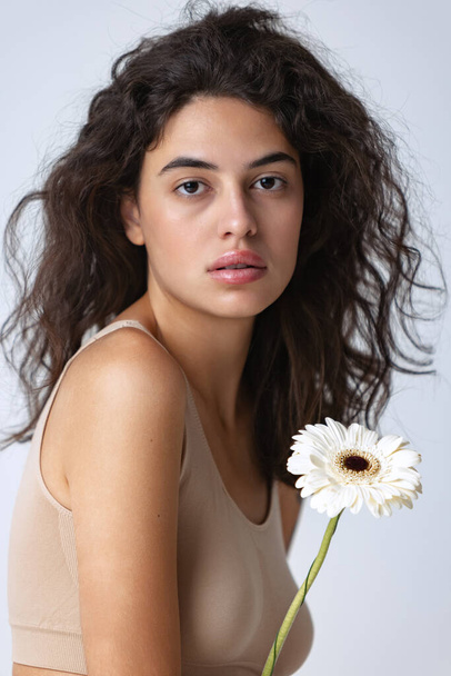 Cropped portrait of beautiful woman with white gerberas posing isolated over gray studio background. Natural beauty - Photo, Image