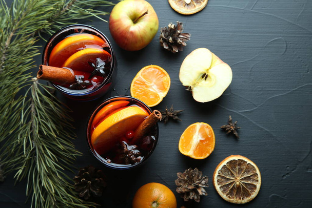 Christmas hot mulled wine in glass with orange, honey, cinnamon sticks and star anise with spices and ingredients. Spicy warm beverage. Seasonal mulled drink. Top view. - Photo, Image