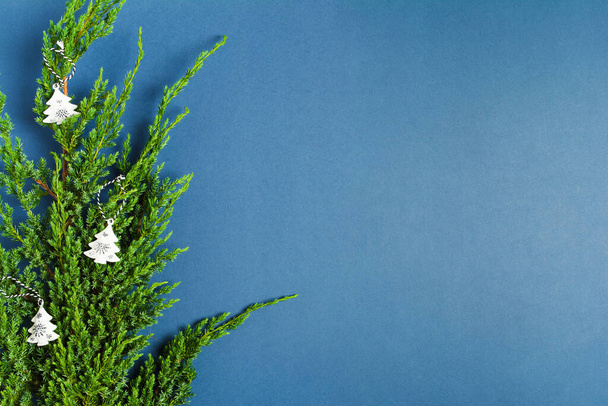 Christmas decoration on green branch of fir tree on blue background - Foto, afbeelding