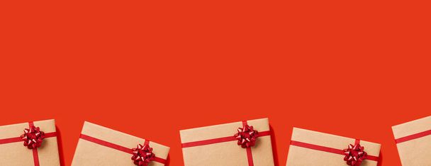 Holiday lahjoja ja esittelee käsite web banneri kopioi tilaa. Lahjapakkaukset kääritty veneet paperi punainen rusetti punaisella pohjalla. Yläkuva. - Valokuva, kuva