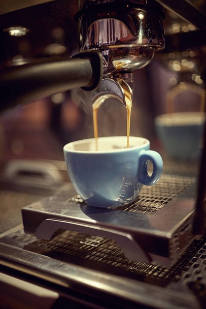 Close-up van een kopje vullen met hete koffie op koffiezetapparaat - Foto, afbeelding