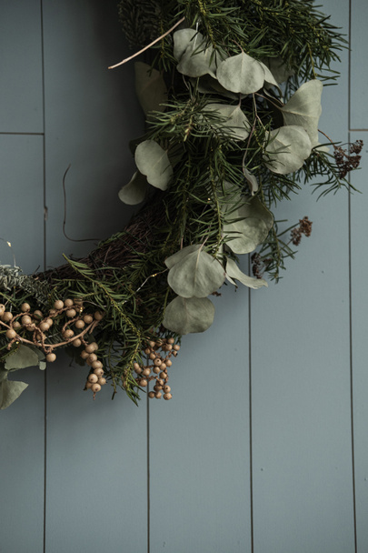 Closeup view of beautiful Christmas wreath made of fir needles hanging on wooden dusty blue wall - Photo, Image