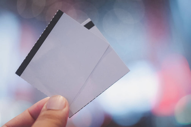 Hände halten eine leere weiße Kinokarte aus Papier. Leere Ticketvorlage, die Sie selbst entwerfen können. - Foto, Bild