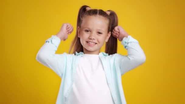 Like and approval. Studio portrait of cute little girl with two ponytails gesturing thumbs up with hands and smiling - Footage, Video