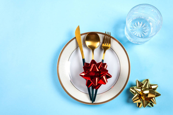 ブルーの背景にモダンな食器や装飾が施されたクリスマステーブルの設定。最上階だ。新年の場所の設定。クリスマス食器。クリスマスの場所の設定。クリスマスディナーカトラリーの装飾 - 写真・画像