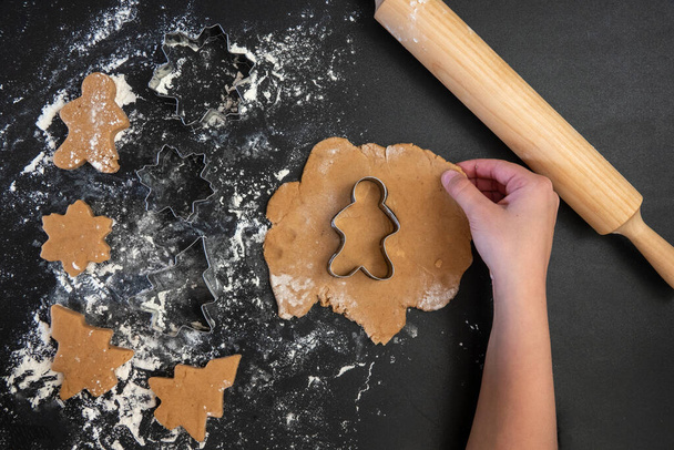 Children's hands make New Year's gingerbread cookies on a wooden table. New Year and Christmas concept. - Photo, image