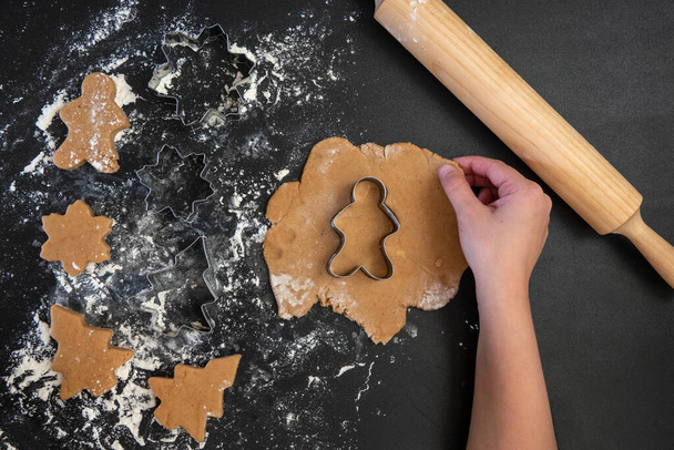 Children's hands make New Year's gingerbread cookies on a wooden table. New Year and Christmas concept. - Foto, Bild
