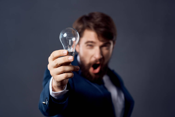 γενειοφόρος άνδρας με κοστούμι με μια λάμπα στα χέρια του μια λαμπρή ιδέα της καινοτομίας - Φωτογραφία, εικόνα