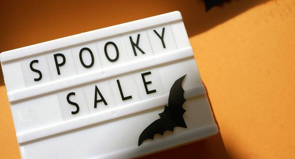 Promoción Halloween. Texto espeluznante venta en caja de luz. Murciélagos de papel y sombras  - Foto, imagen