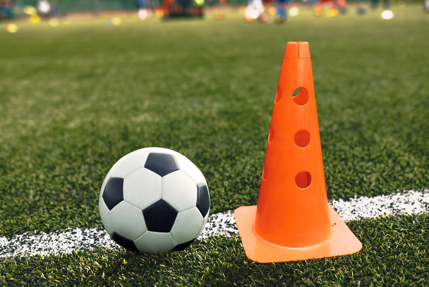 サッカーボールとトレーニングコーンはサッカーピッチサイドラインに横たわっています。学校練習用サッカートレーニング機器ピッチ - 写真・画像