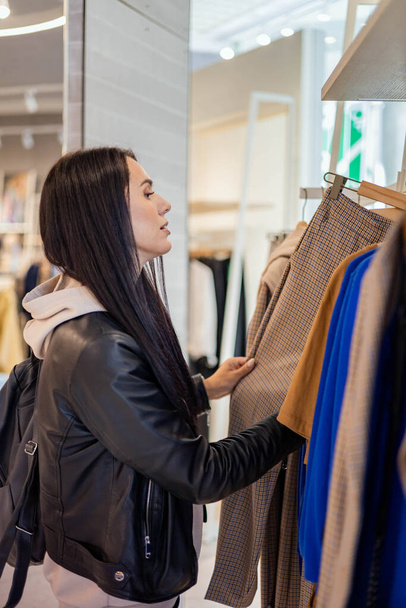Modern woman choosing clothes at fashionable store boutique discount enjoying leisure hobby - Фото, зображення