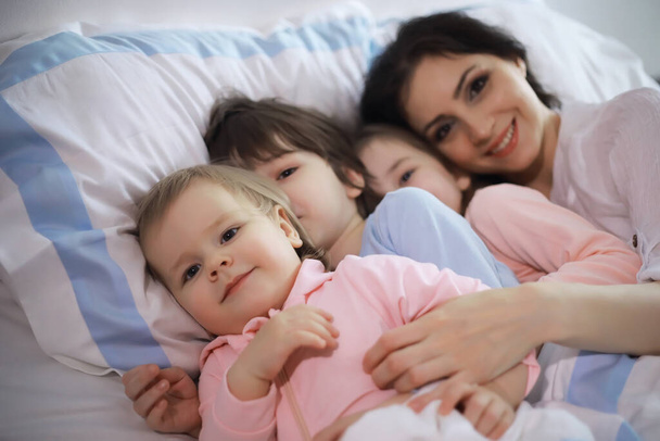 Uma família com crianças se divertindo na cama sob as cobertas durante as férias de Natal. - Foto, Imagem