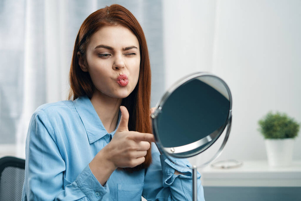 woman looking in the mirror cosmetics personal care - 写真・画像