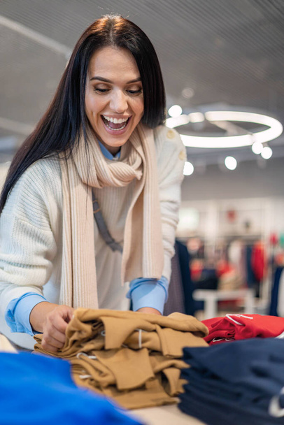 Overjoyed shopaholic woman grabbing clothes at seasonal discount black friday sale - Фото, изображение