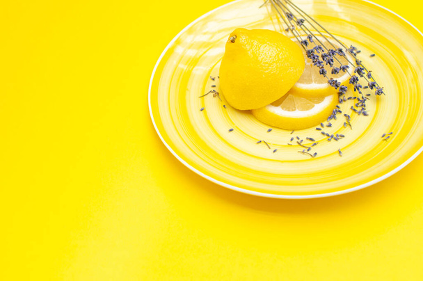 Yellow juicy lemon and lavender herb on a yellow plate sliced beautifully. Fruit serving concept  - Foto, Bild
