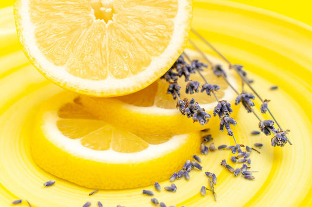 Yellow juicy lemon and lavender herb on a yellow plate sliced beautifully. Fruit serving concept  - Фото, изображение