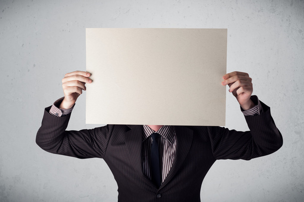 Businessman holding in front of his head a paper with copy space - Fotoğraf, Görsel